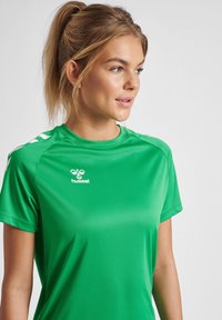 T-shirt de sport vert en tissu lisse, avec des manches courtes et un logo blanc à l'avant. Design simple sans motifs.