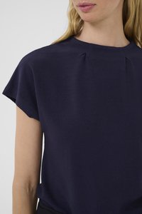 Tmavě modrá krátká halenka s krátkým rukávem, texturovaná látka, kulatý výstřih, s jemnými sklady na rameni. Jednoduchý design bez viditelného kovového příslušenství nebo vzorů.