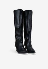 Botas de cuero negras hasta la rodilla con puntera puntiaguda y tacón delgado; textura suave con una costura mínima y sin herrajes visibles.