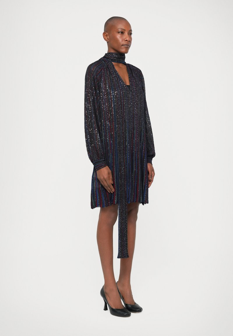 Black and multicolored sequined dress with long sleeves, high collar, and a tie detail at the neckline, featuring a loose fit and knee length.
