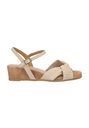 Beige suede wedge sandal with knotted front strap, ankle strap, and buckle closure, featuring a medium heel and cushioned footbed.