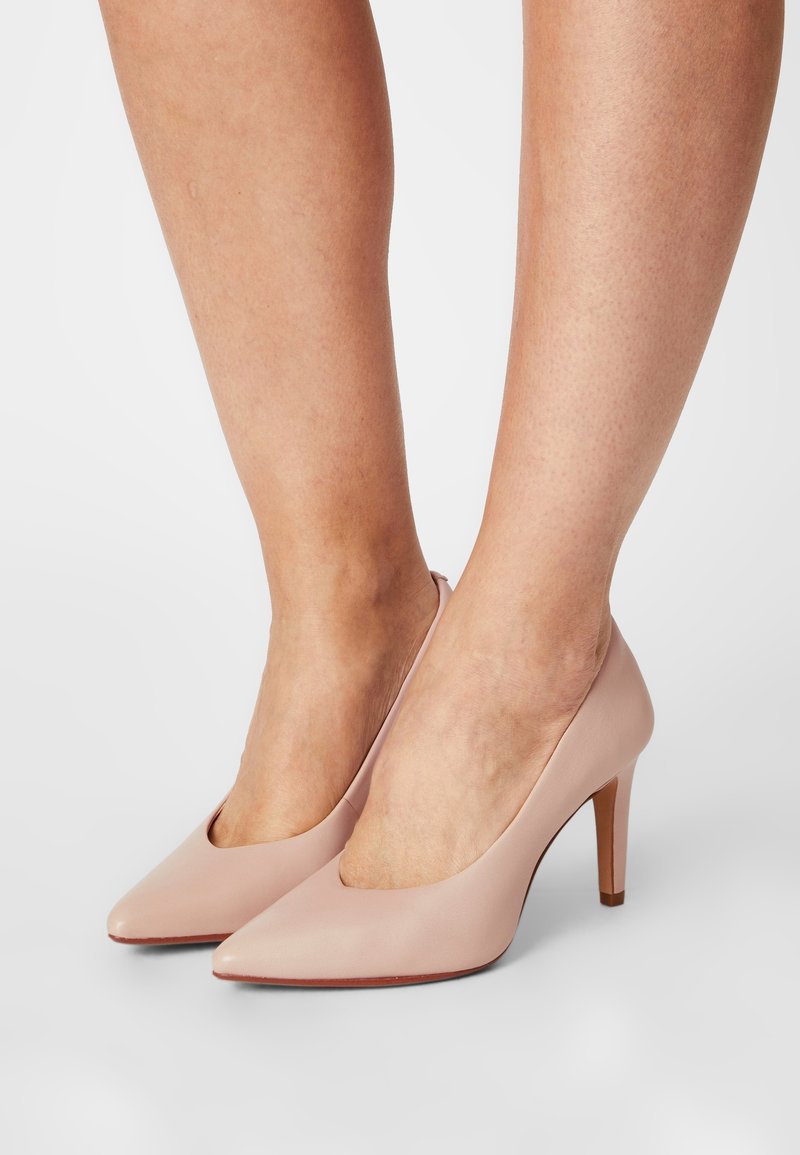 Chaussures à talons hauts rose clair avec un bout pointu et un design découpé. Fabriquées en matériau lisse avec un talon fin.