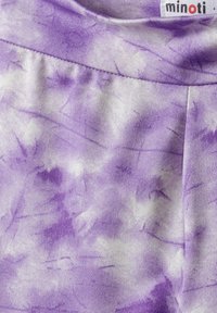 Ljubičasta tkanina s efektom tie-dye, koja sadrži svjetlije i tamnije vrtloge, meku teksturu i elastičnu trakicu u struku. Na oznaci piše "minoti."