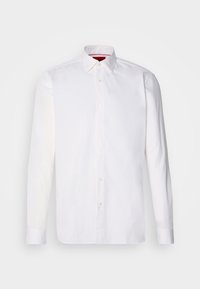 Camicia bianca a maniche lunghe in cotone. Presenta un colletto classico, chiusura frontale con bottoni e polsini. Tessuto liscio senza motivi.