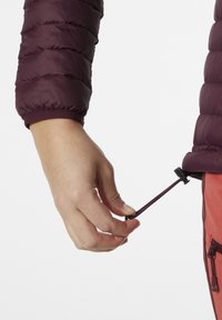 Burgundský naducaný rukáv s elastickým lemem, nastavitelná šňůra v ruce, kontrastní oranžové kalhoty se zipovými kapsami.