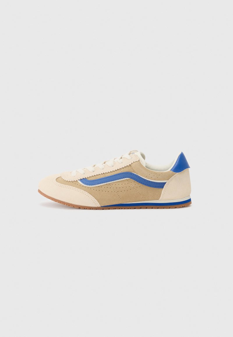 Light tan suede sneaker with a blue side stripe and heel accent. Rounded toe, flat laces, and perforated detailing on the upper. Rubber outsole.