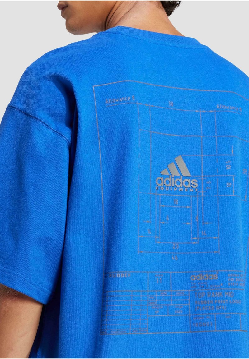 Blåt bomulds T-shirt med et stort trykt design i guld med tekniske tegninger og tekst. Løs pasform med korte ærmer og rund hals.