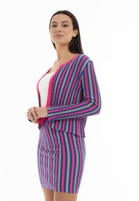 Conjunto de cárdigan y falda a rayas en azul, rosa y beige. Tejido ligero con textura acanalada. Presenta un frente sin botones y mangas largas.