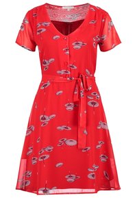 Červené šaty s krátkými rukávy a výstřihem do V, s knoflíkovým zapínáním vpředu a zavázaným pasem. Látka má květinový vzor s deštníky.