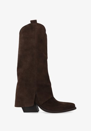 Brązowy zamszowy botek za kostkę z ostro zakończonym noskiem, luźnym fasonem i unikalnym geometrycznym obcasem. Posiada pętelkę z tyłu.