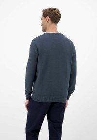 Dunkelblauer Pullover mit strukturiertem Strick, Rundhalsausschnitt und langen Ärmeln, über dunklen Hosen getragen, von hinten betrachtet.