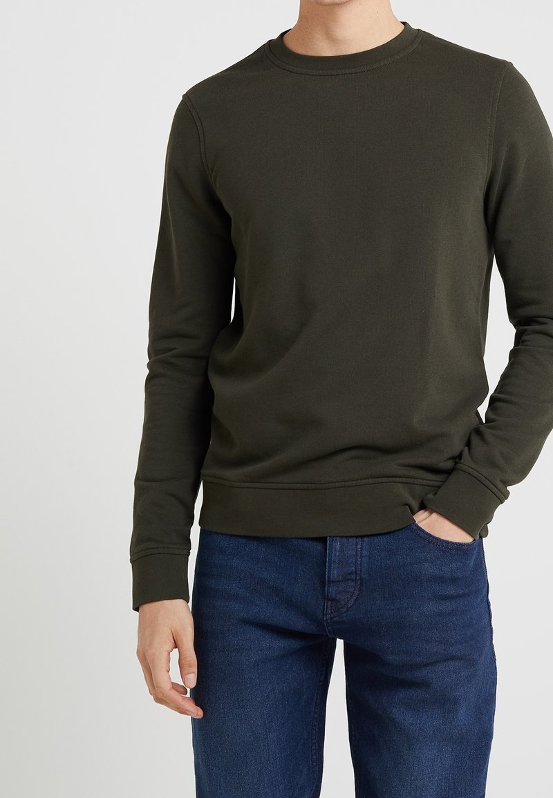 Felpa verde oliva con maniche lunghe, coltondo, polsini e orlo a costine. Abbinate a jeans blu scuro, con tessuto liscio e design casual.