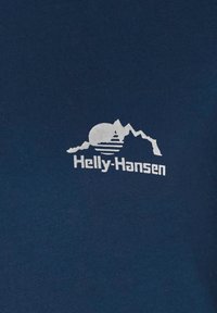Camiseta de algodón azul marino con un gráfico blanco de montañas y el sol, con "Helly-Hansen" impreso en una fuente en negrita debajo.