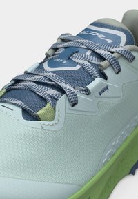 Αθλητικό παπούτσι σε ανοιχτό μπλε και πράσινο χρώμα με κορδόνια με μπλε σχέδια και την επιγραφή "ULTRA" σε μπλε ταμπελάκι στη γλώσσα.