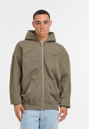 Olivovo zelená mikina na zips z mäkkého materiálu, s predným vreckom, kapucňou a malým logom na ľavej strane hrudníka. Dizajn s voľným strihom.