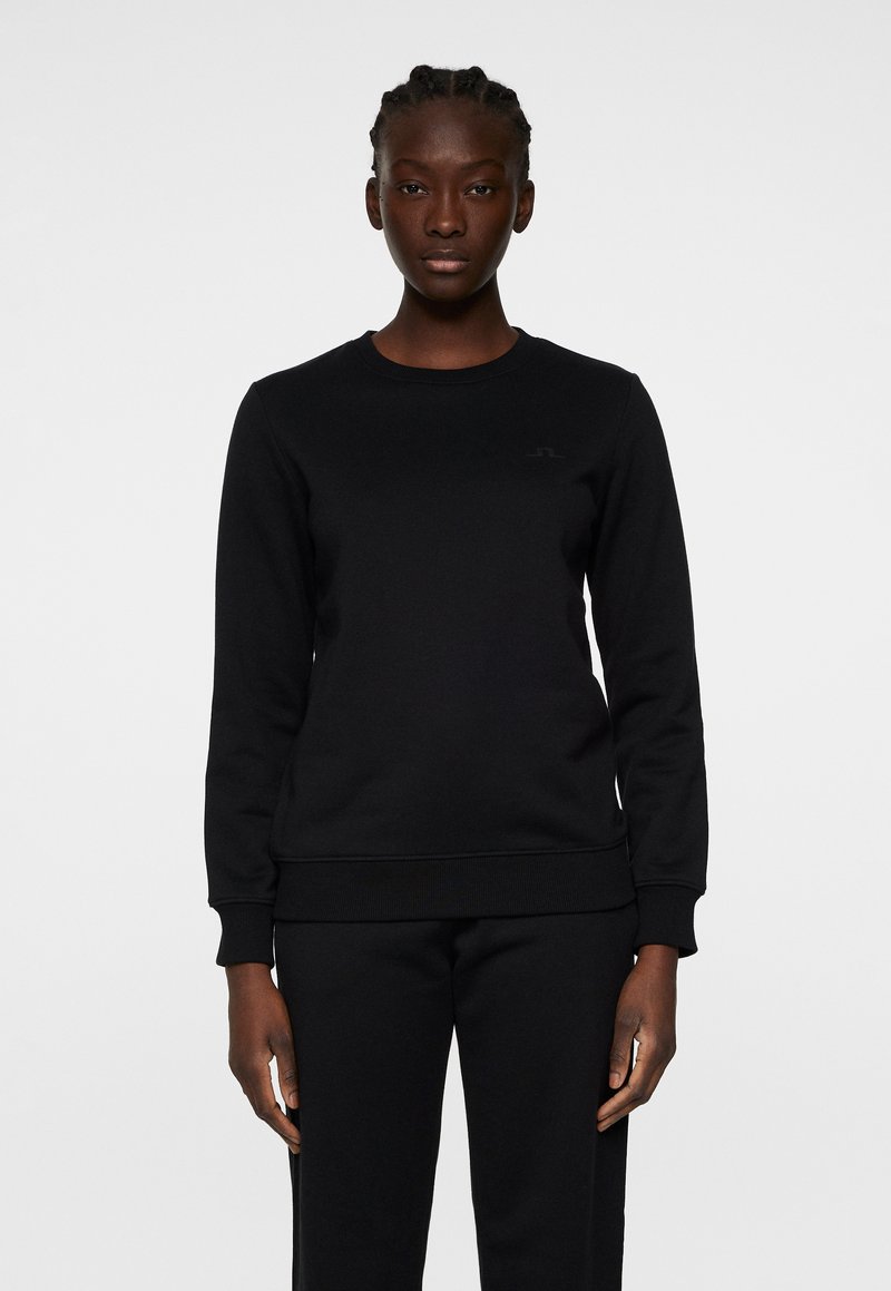 Svart sweatshirt med rund hals, långa ärmar och ribbade manschetter. Tillverkad av texturerat tyg, med en subtil logotyp på bröstet.