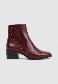 Bottines en cuir bourgogne avec un bout pointu, un talon bloc, des clous décoratifs et un design embossé sur le côté. Texture lisse.