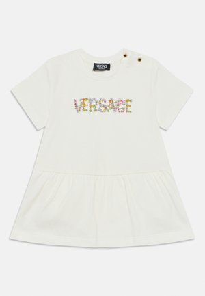 Balta trumpomis rankovėmis suknelė su raukiniais apačioje, gėlių „Versace“ logotipas ant krūtinės ir dvi dekoratyvinės auksinės sagos ant kairiojo peties.