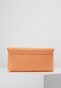 Oranžová semišová kabelka se zřetelným obdélníkovým tvarem, se sklápěcím víkem a švadlovými detaily podél okrajů.