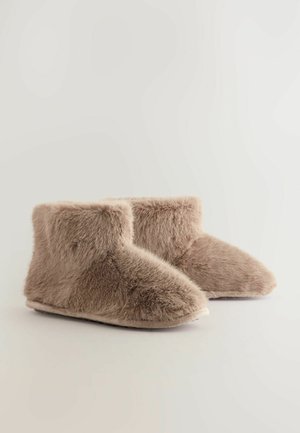 Pantofole in pelliccia sintetica marrone, morbide, con un gambo corto e arrotondato e una forma della punta curvata; presentano una texture soffice e una suola piatta e antiscivolo.