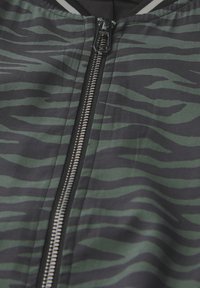 Veste bomber de couleur vert foncé avec des rayures zèbre noires, dotée d'une fermeture éclair en métal et d'un col côtelé, fabriquée dans un tissu lisse et léger.