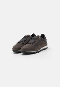 Zapatillas de gamuza en gris oscuro con detalles en negro, que presentan seis ojales, cordones texturizados y una suela de goma con surcos para mayor tracción.