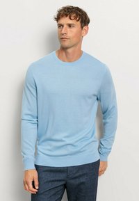 Helles blaues, langärmliges Sweatshirt aus glattem Strickstoff mit Rundhalsausschnitt sowie gerippten Bündchen und Saum, kombiniert mit dunklen Hosen.