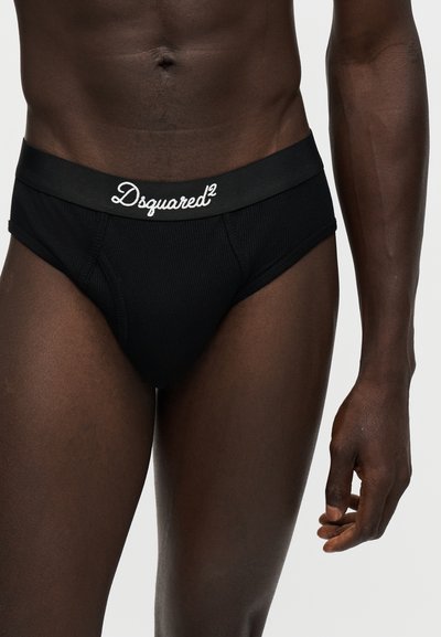 Άνδρας που φοράει μαύρα εσώρουχα Dsquared2, δείχνοντας τον κορμό και το πάνω μέρος των ποδιών με ορατό λογότυπο στη μέση.