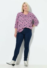 Růžovo-námořnický vzorovaný top s tříčtvrtečními rukávy, paired s tmavě modrými skinny jeans a metalickými kotníkovými botami. Jednoduché pozadí.