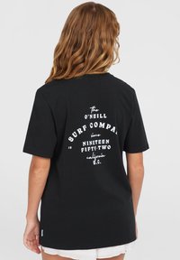 Must t-särk mustast puuvillast, millel on valge graafiline trükk seljal, mis sisaldab "O'Neill Surf Company" ja "Nineteen Fifty-Two, California S.C.".