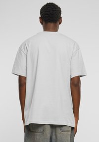 Grey cotton t-shirt with a relaxed fit, short sleeves, round neckline, and no visible graphics. Worn with loose-fitting jeans.