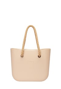 Beige O Bag-tas gemaakt van een rubberachtig materiaal, met een gladde textuur, ronde vorm en katoenen touwhandvatten met metalen accenten.