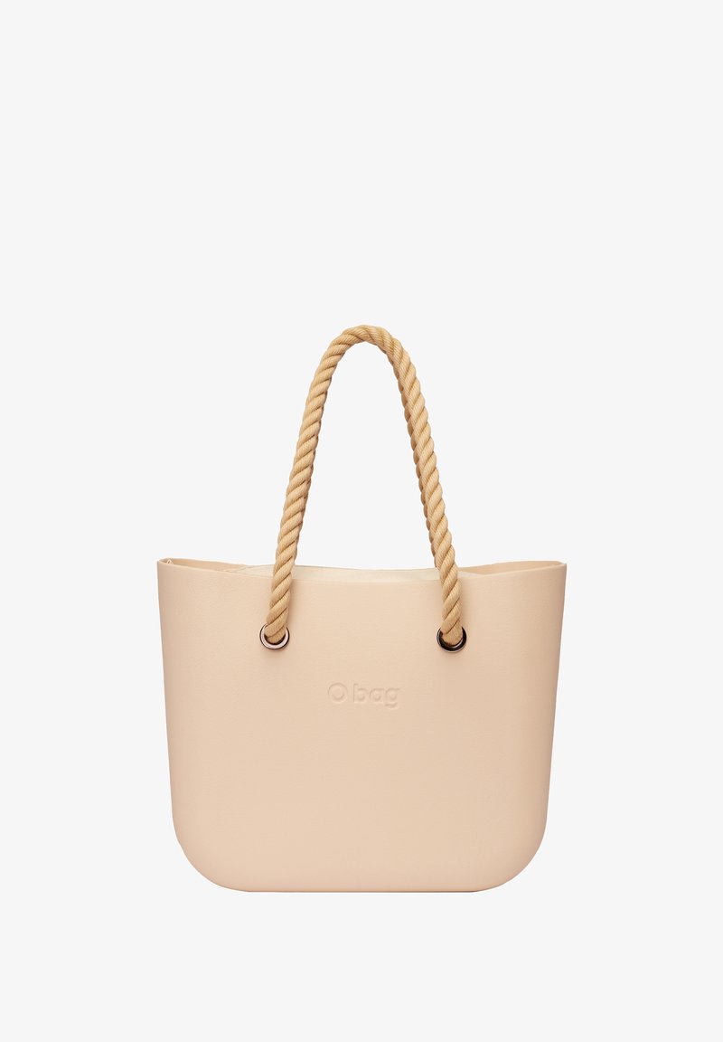 Beżowa torba O Bag wykonana z materiału przypominającego gumę, charakteryzująca się gładką fakturą, zaokrąglonym kształtem oraz bawełnianymi uchwytami z metalowymi akcentami.