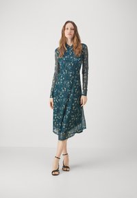 Turkoosi kukallinen midi-mekko, jossa on pitkät läpinäkyvät hihat, kaulus ja verkkomainen helma. Mekossa on herkkä kuvio pienistä kukista koko matkalla.
