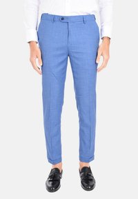 Pantaloni tailored blu chiaro realizzati in tessuto testurizzato, con chiusura a un bottone e taglio dritto. Indossati con mocassini neri.