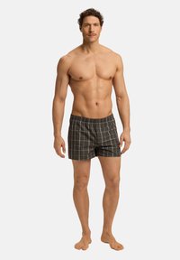 Boxer shorts para hombre en tejido verde oscuro con un patrón de cuadros blancos. Cintura elástica, material típicamente de algodón, ajuste casual.