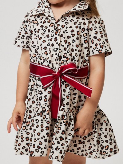Leopard print dress with short sleeves, a pointed collar, and a cinched waist tied with a red ribbon. Flared skirt and textured fabric.