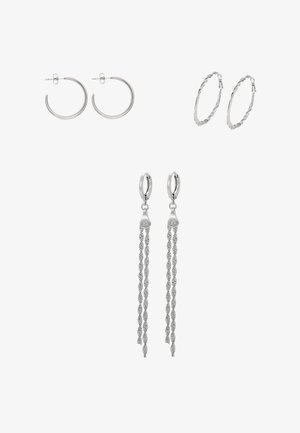 Drie paar zilveren oorbellen: gladde ronde ringen, gedraaide textuurringen en lange ringen met hangende gedraaide kettingen.