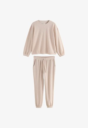 Ensemble de détente côtelé beige clair comprenant un pull à col rond avec des poignets élastiques et un pantalon à taille cordon avec poches latérales.