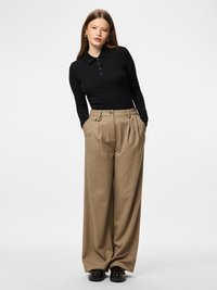 Μαύρο ριμπ μακρυμάνικο πόλο μπλουζάκι με πατιλέτα με κουμπιά, συνδυασμένο με μπεζ παντελόνια φαρδιάς γραμμής και μαύρα παπούτσια. Απλός, καλοραμμένος σχεδιασμός.