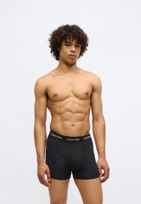 Boxeri scurți negri din bumbac cu un brâu elastic moale, având logo-ul Calvin Klein. Construiți cu o croială mulată și o textură netedă.
