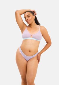 Lichtpaarse lingerie set met contrasterende pastelblauwe accenten. De bh heeft dunne bandjes en een sleutelgatdetail; de slips hebben een hoge uitsnijding.
