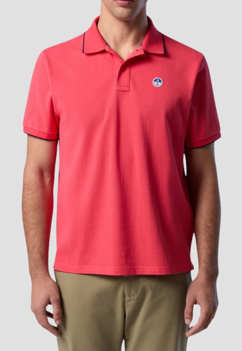 Polo rosso a tinta unita, maniche corte e colletto. Presenta un bordo a contrasto e un piccolo logo rotondo sul petto.