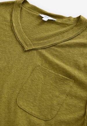 T-shirt vert olive en v, fabriqué en tissu doux, avec une poche avant et des détails à bords bruts le long de l'encolure.