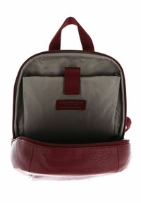 Sac à dos en cuir bordeaux avec une finition texturée, une poignée supérieure et un intérieur doublé de tissu. Comprend une étiquette en cuir à l'intérieur.