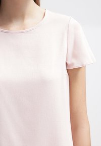 Ljust rosa kortärmad topp med en strukturerad tyg och rund halsringning. Enkel, avslappnad passform med en mjuk yta.