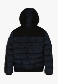 Mörkblå och svart vadderad jacka med huva, kviltad design och ribbade ärmslut och midja, visad från baksidan.