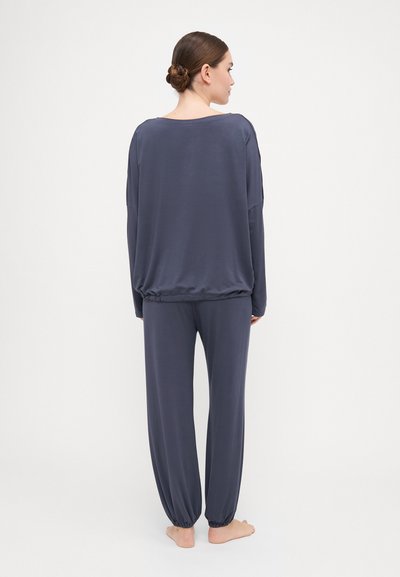 Navy lounge set made of soft fabric; features a loose-fitting long-sleeve top with a wide neckline and tapered pants with gathered hems.