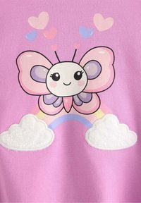 Tessuto rosa con una farfalla dei cartoni animati dalle grandi ali a forma di cuore, un volto sorridente e un arcobaleno con soffici nuvole bianche.