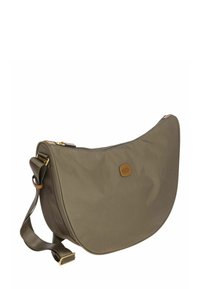 Sac d'épaule en forme de croissant vert olive avec une sangle réglable en cuir marron foncé et une petite étiquette rectangulaire en cuir avec logo.
